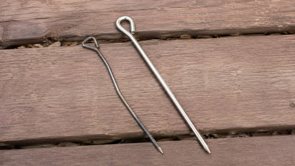Side-by-side comparison of a bent stock tent stake next to a straight upgraded steel stake